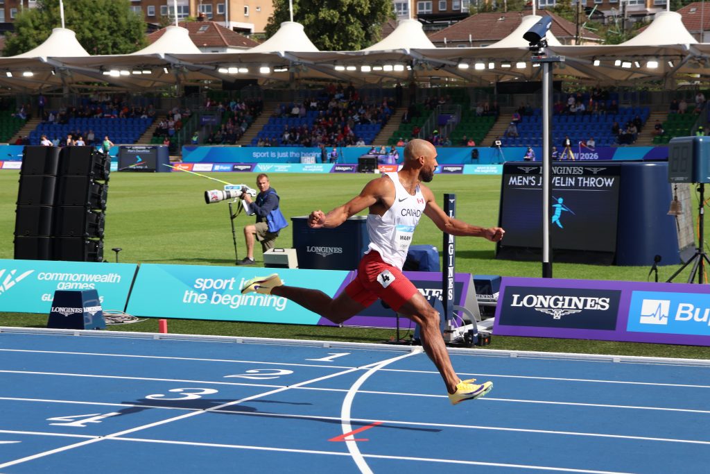 Damian Warner crossing the finish line in the Commonwealth Games decathlon 100m